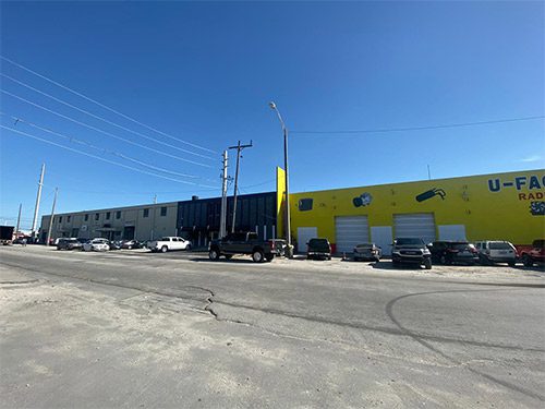 A large warehouse with cars parked in front of it.