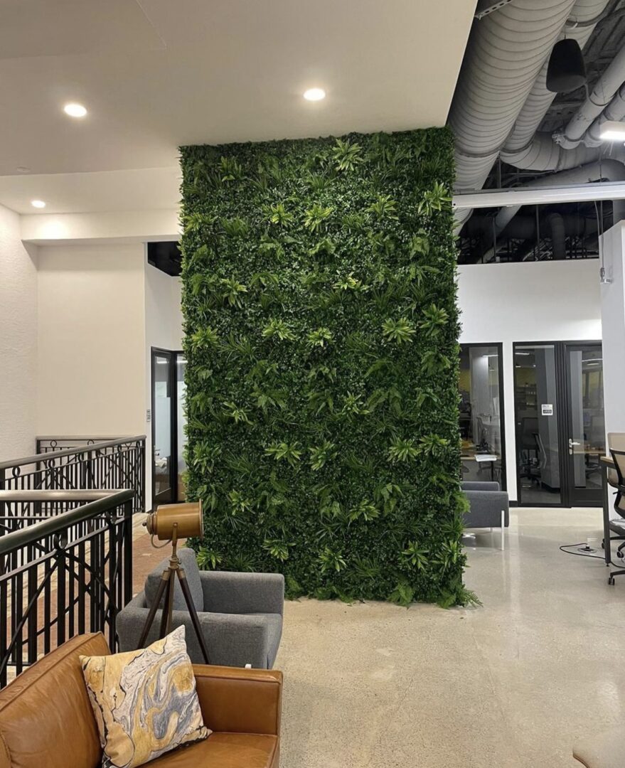 A room with a wall of plants and chairs