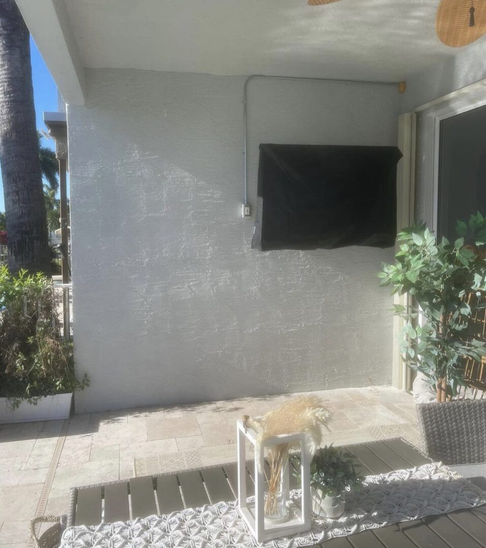 A television mounted on the wall outside of a house.