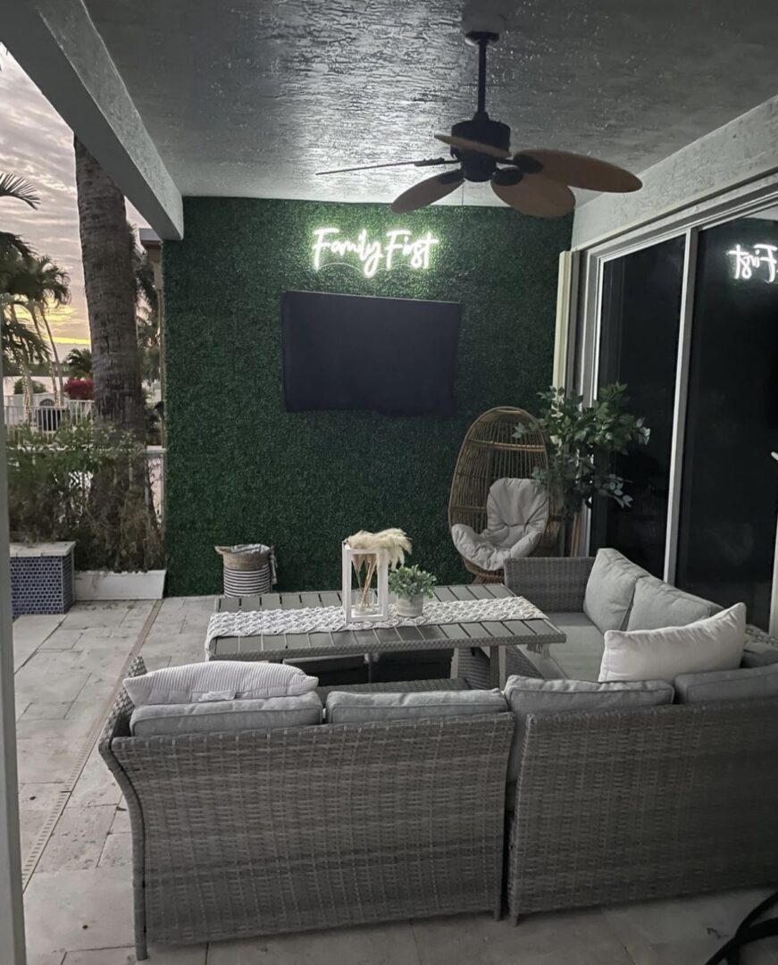 A patio with a table and chairs, television on the wall.