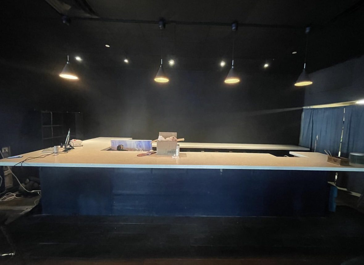 A wrestling ring with lights above it and a person laying on the ground.