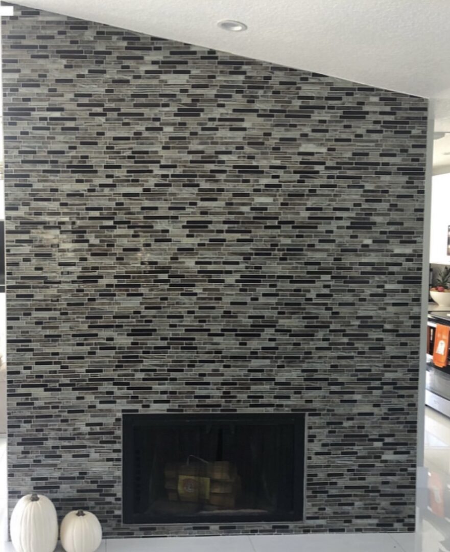 A fireplace with a black and white brick wall