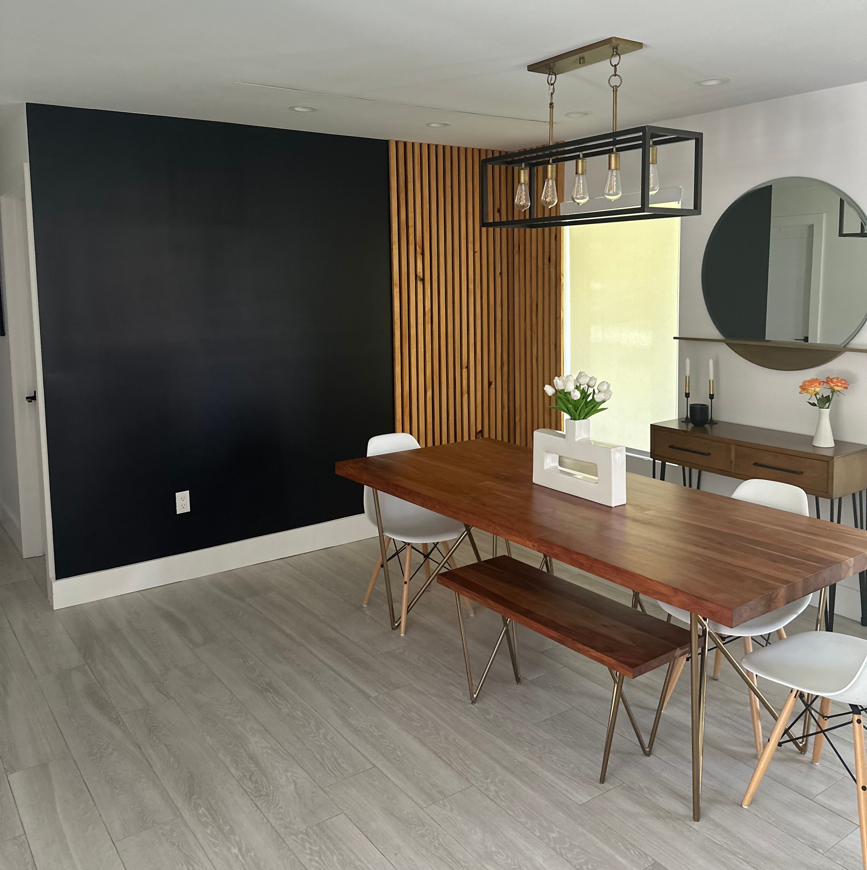 A dining room with a table and chairs, a mirror and a window.